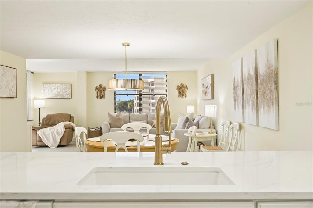 A kitchen sink and faucet overlook an open-concept dining and living area with neutral decor — 5780 MIDNIGHT PASS ROAD UNIT 407, SARASOTA, FL