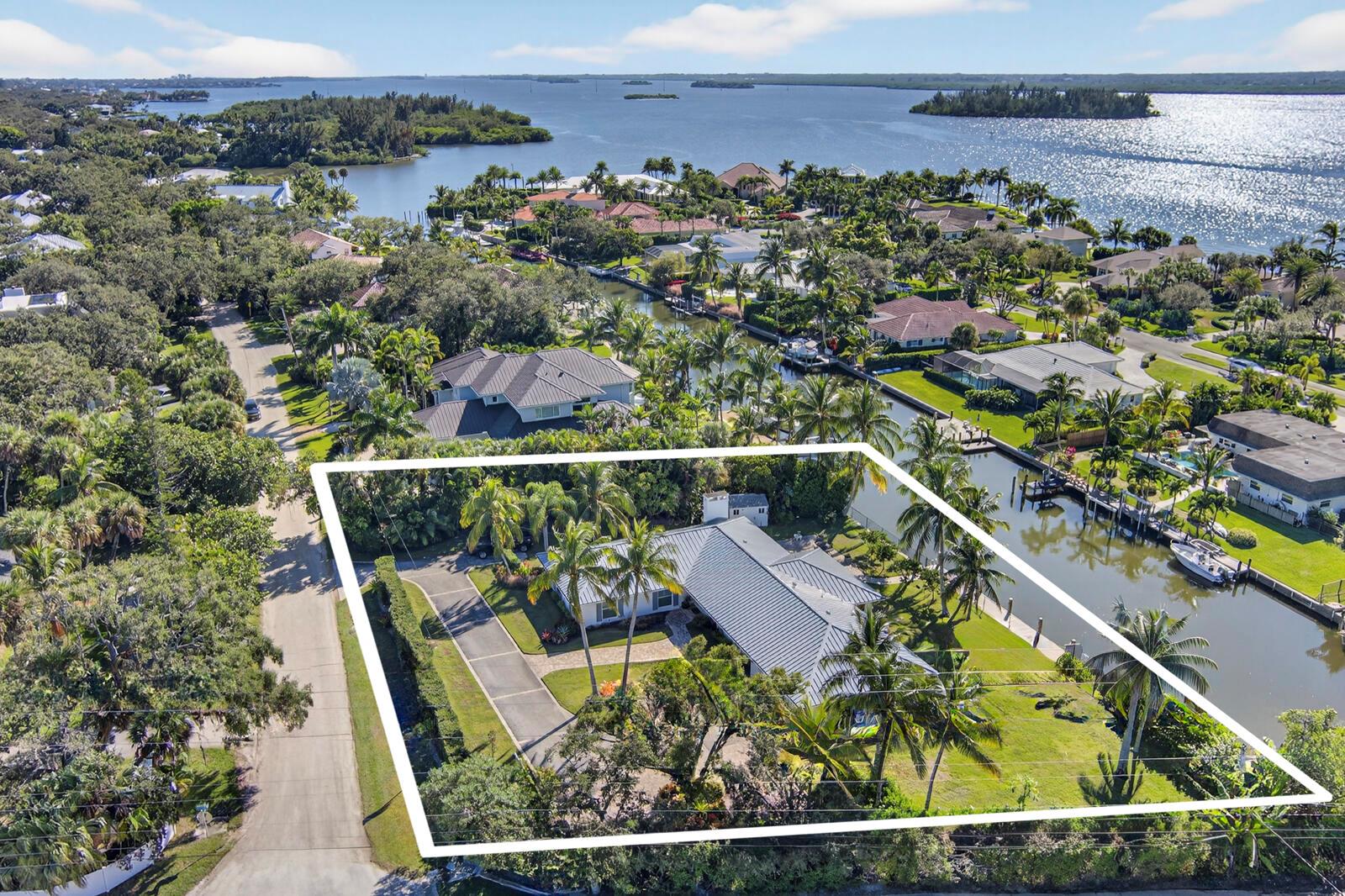 An aerial view shows a single-story house with a metal roof on a waterfront lot — VERO BEACH, FL