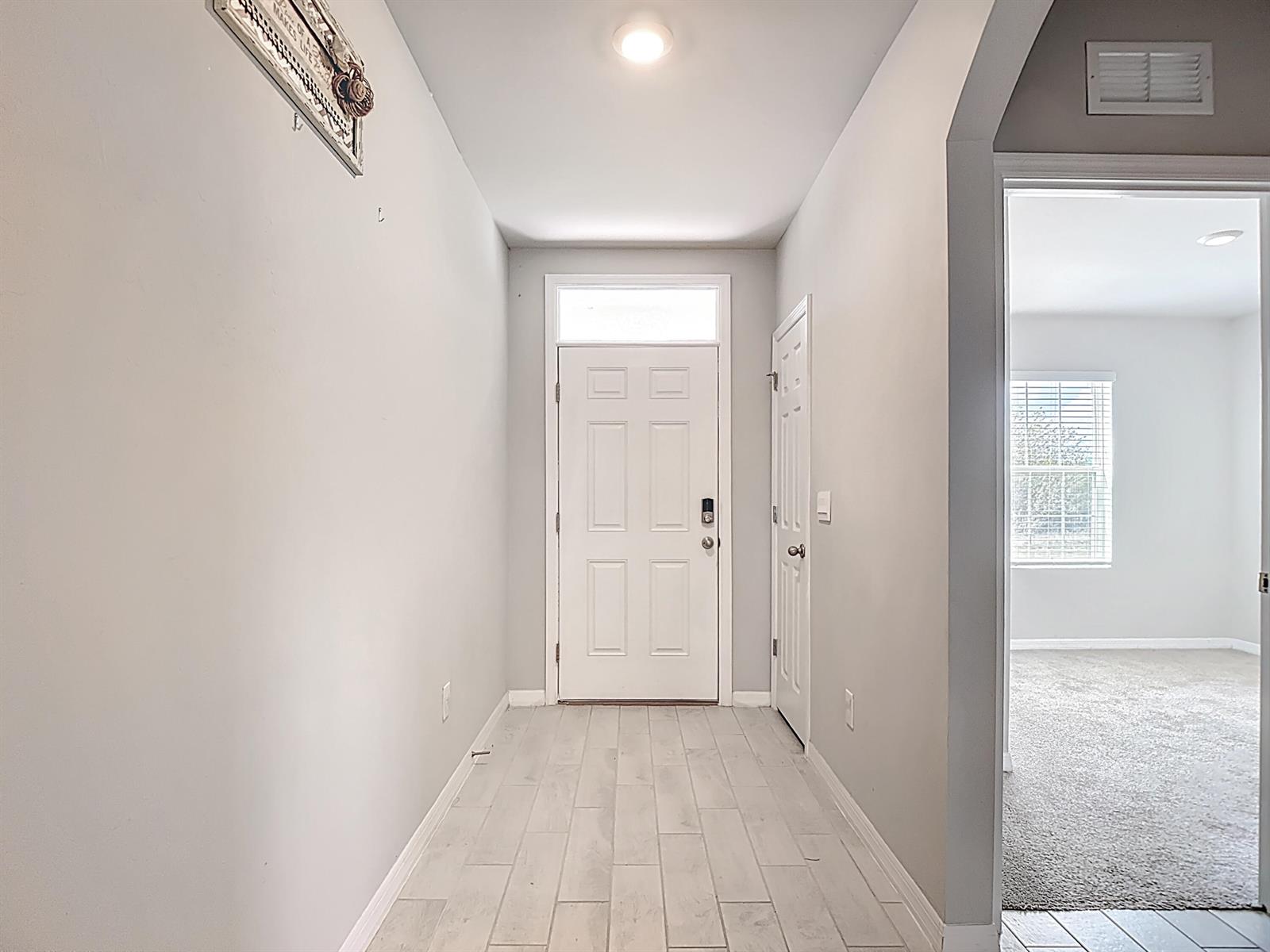 A bright entryway features light-colored wood-look tile flooring, a white front door, and gray walls — 524 W Glendale Avenue, FL 33935, FL