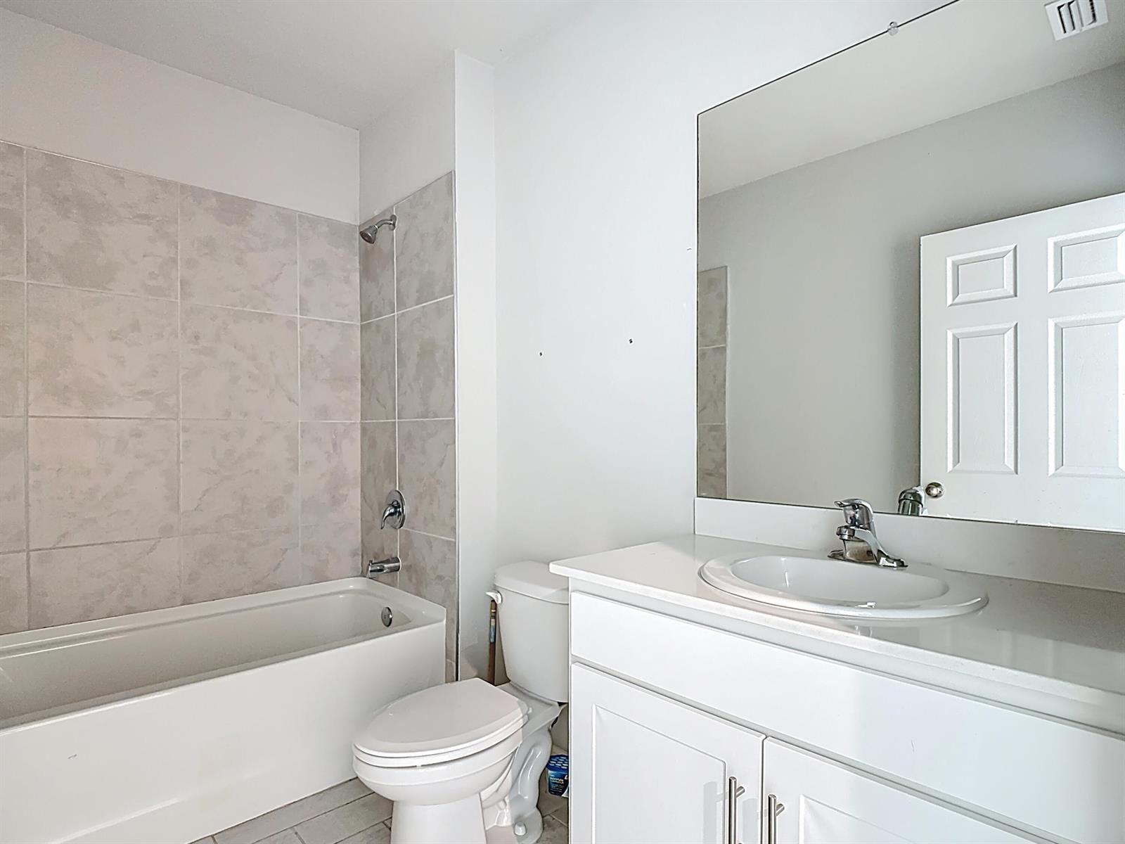 A bathroom features a white vanity, a toilet, and a bathtub with tiled walls — 524 W Glendale Avenue, FL 33935, FL