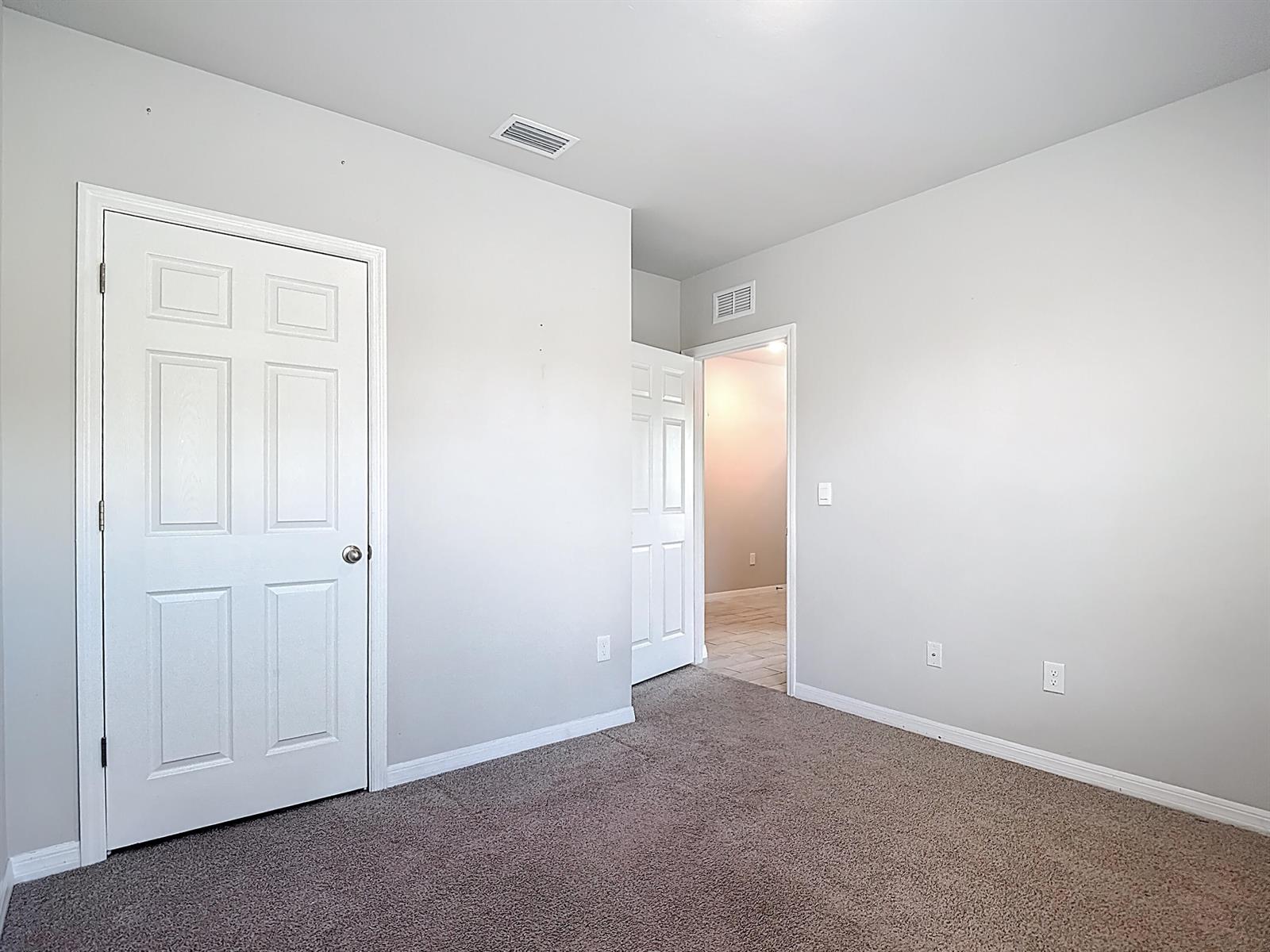 An empty room with gray walls, carpeted flooring, and two white interior doors — 524 W Glendale Avenue, FL 33935, FL