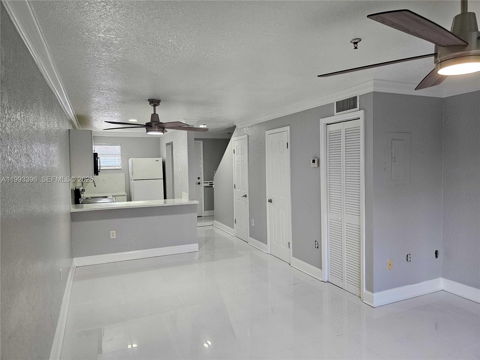 A room with white tile floors, gray walls, two ceiling fans, and a kitchen area — 8027 NW 8th St # 17, Miami FL 33126, MIAMI, FL
