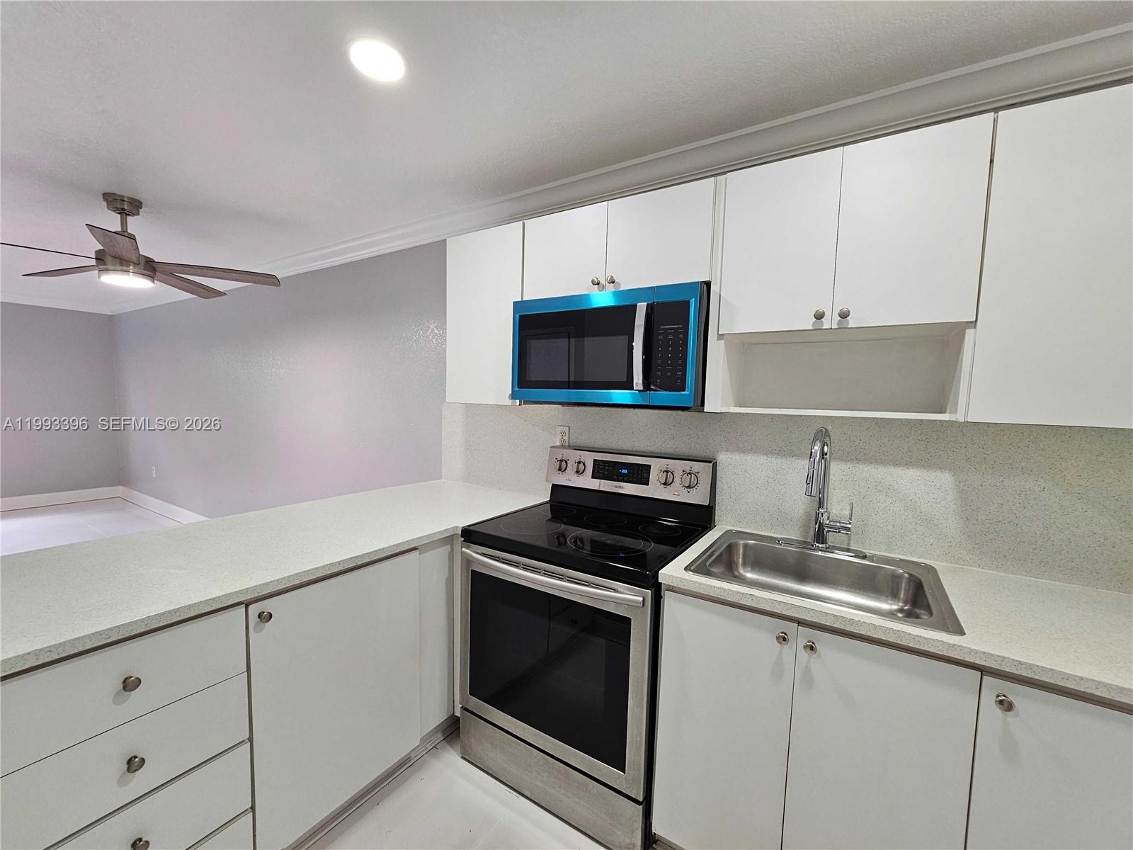A kitchen features white cabinets, stainless steel appliances, and light-colored countertops — 8027 NW 8th St # 17, Miami FL 33126, MIAMI, FL