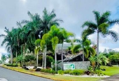 A stone entrance sign surrounded by palm trees and landscaping sits beside a paved road — 120 AVENIDA LA SIERRA UNIT F6102, SAN JUAN, PR