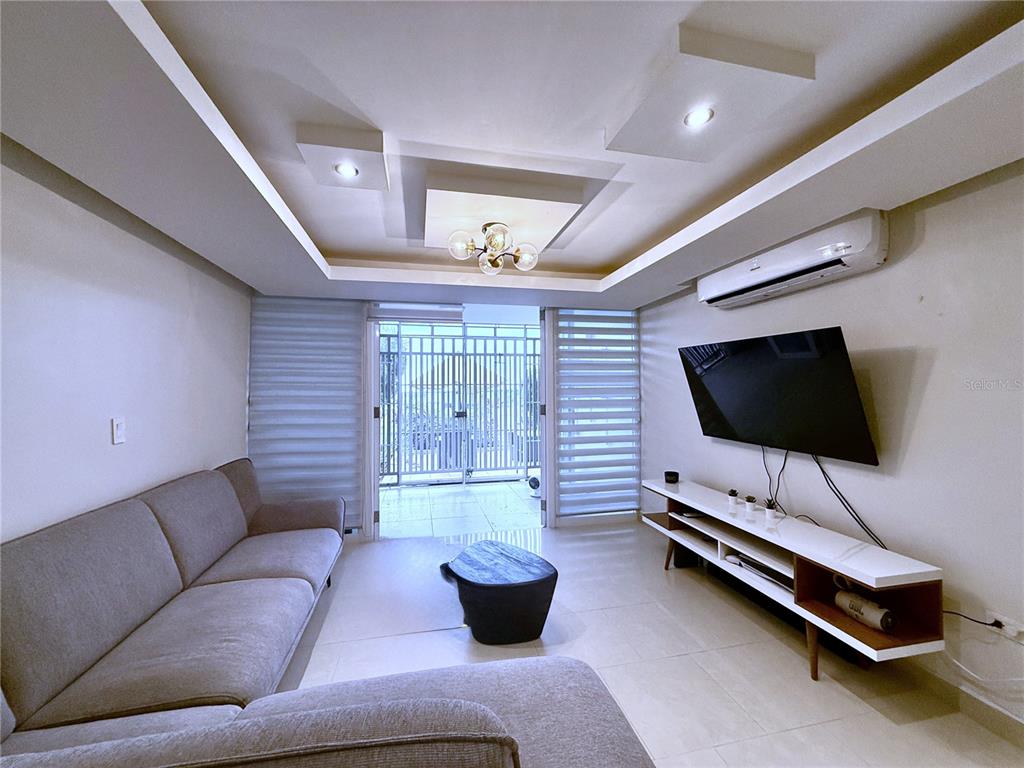 A living room features a gray sectional sofa, a wall-mounted television, and a tray ceiling — 120 AVENIDA LA SIERRA UNIT F6102, SAN JUAN, PR