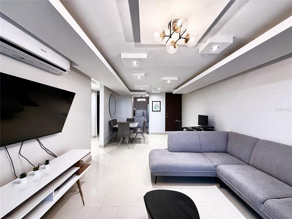 A modern living room features a gray sectional sofa, a wall-mounted television, and tile flooring — 120 AVENIDA LA SIERRA UNIT F6102, SAN JUAN, PR