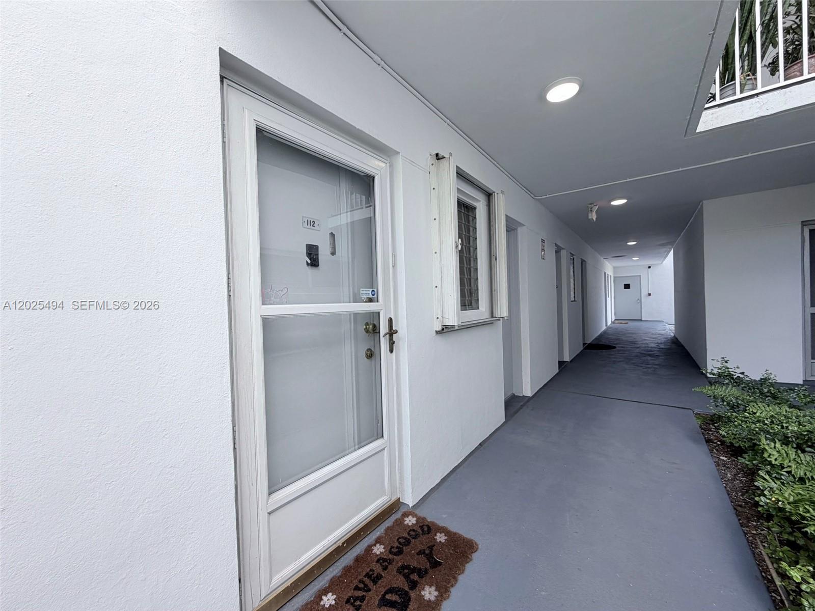 A white exterior door labeled 112 opens onto a covered concrete walkway — 9159 SW 77th Ave # 112, Miami FL 33156, MIAMI, FL