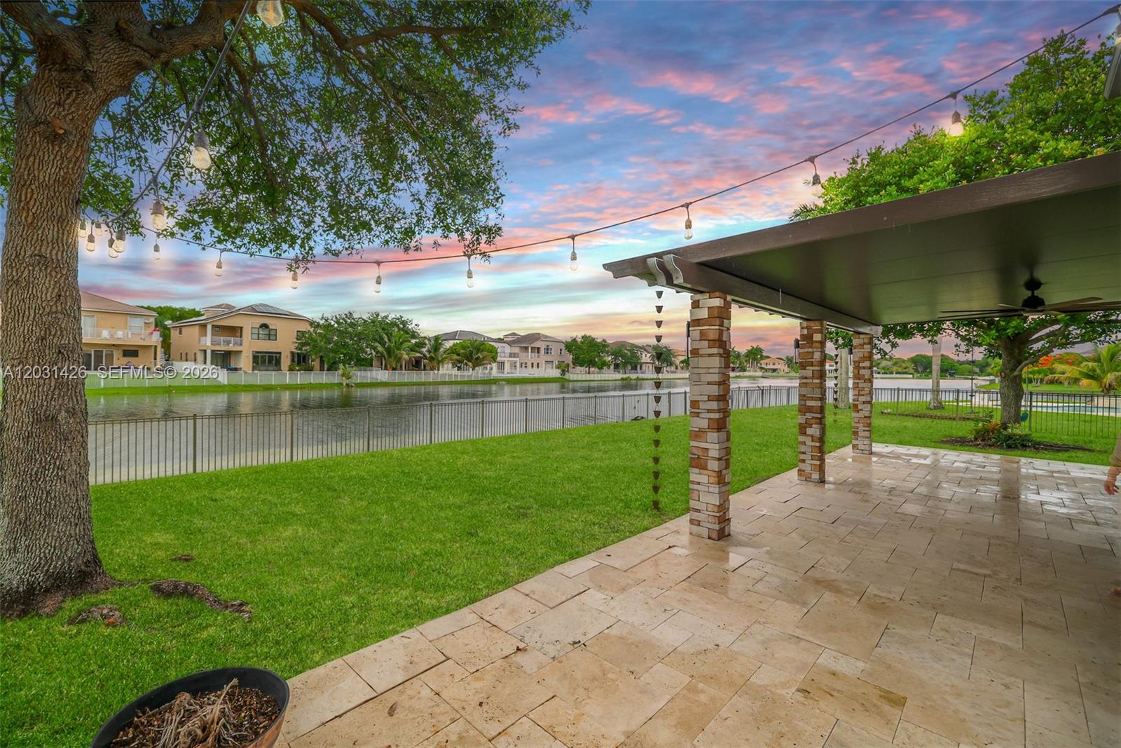 A paved patio with a covered roof overlooks a grassy lawn and a lake — 15815 SW 52nd Ct, Miramar FL 33027, MIRAMAR, FL