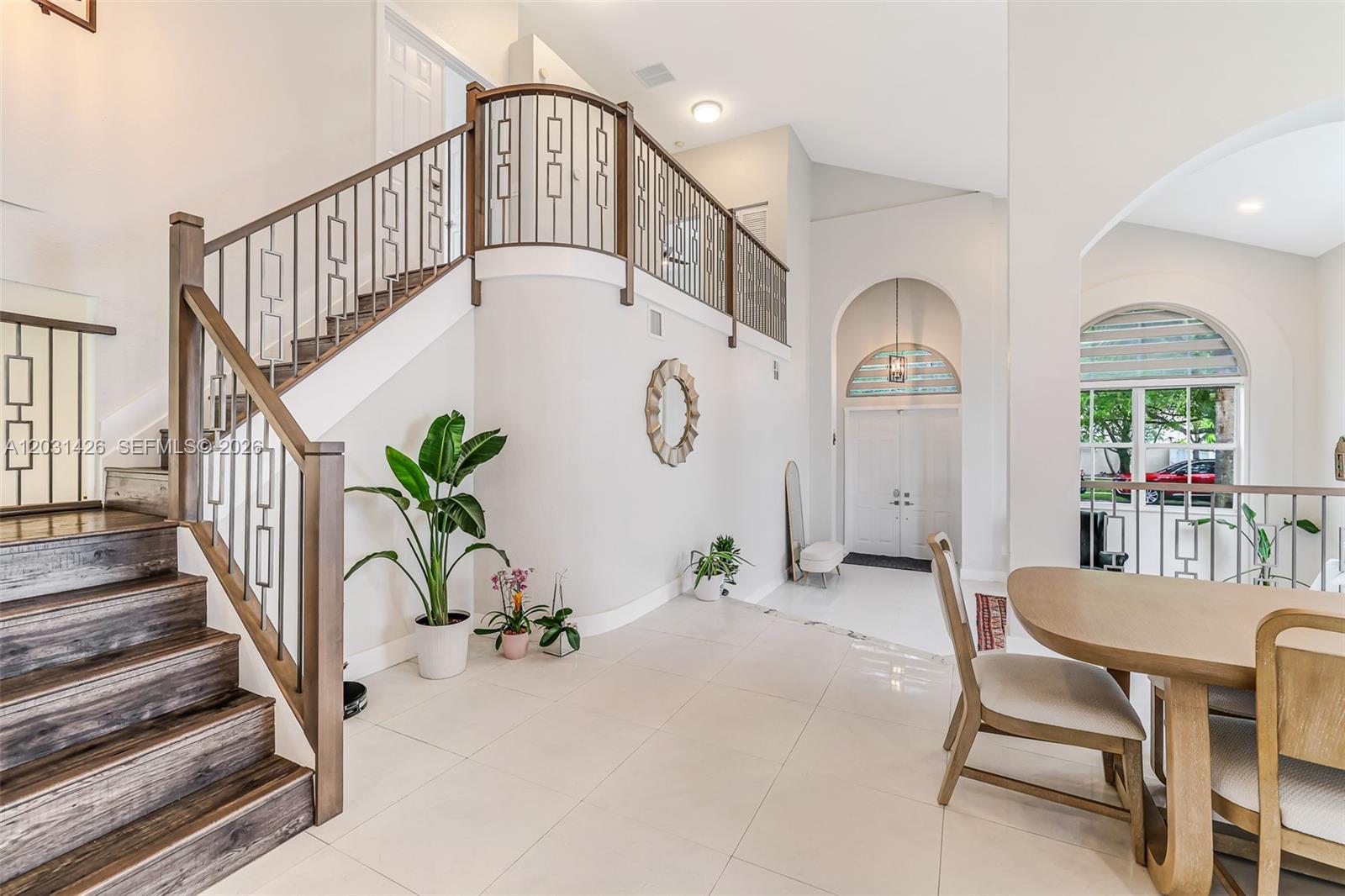 A bright foyer features a curved staircase with metal railings and light tile flooring — 15815 SW 52nd Ct, Miramar FL 33027, MIRAMAR, FL