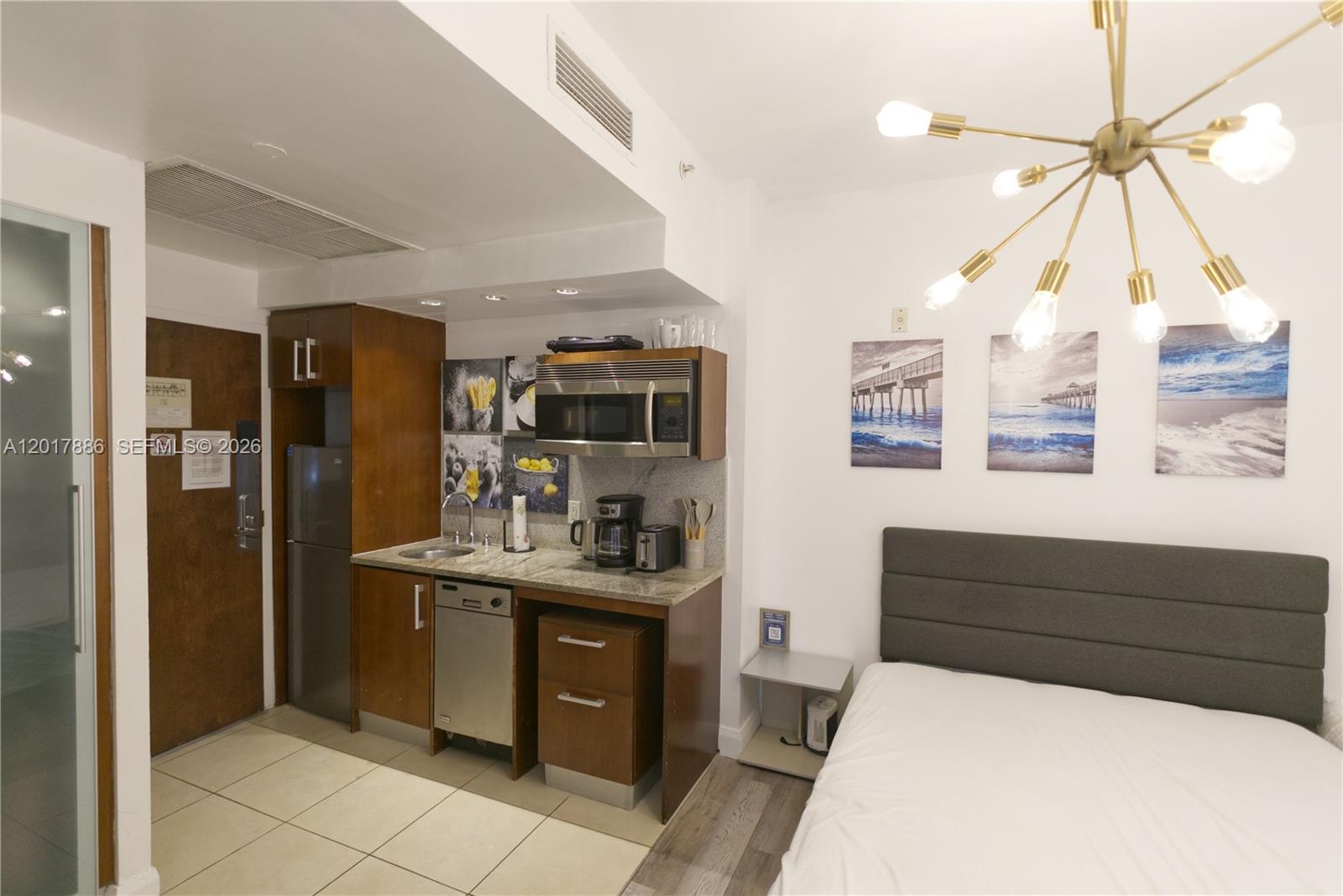 A studio apartment features a kitchenette with stainless steel appliances and an adjacent bed — 1036 Ocean Dr # B308, Miami Beach FL 33139, MIAMI BEACH, FL