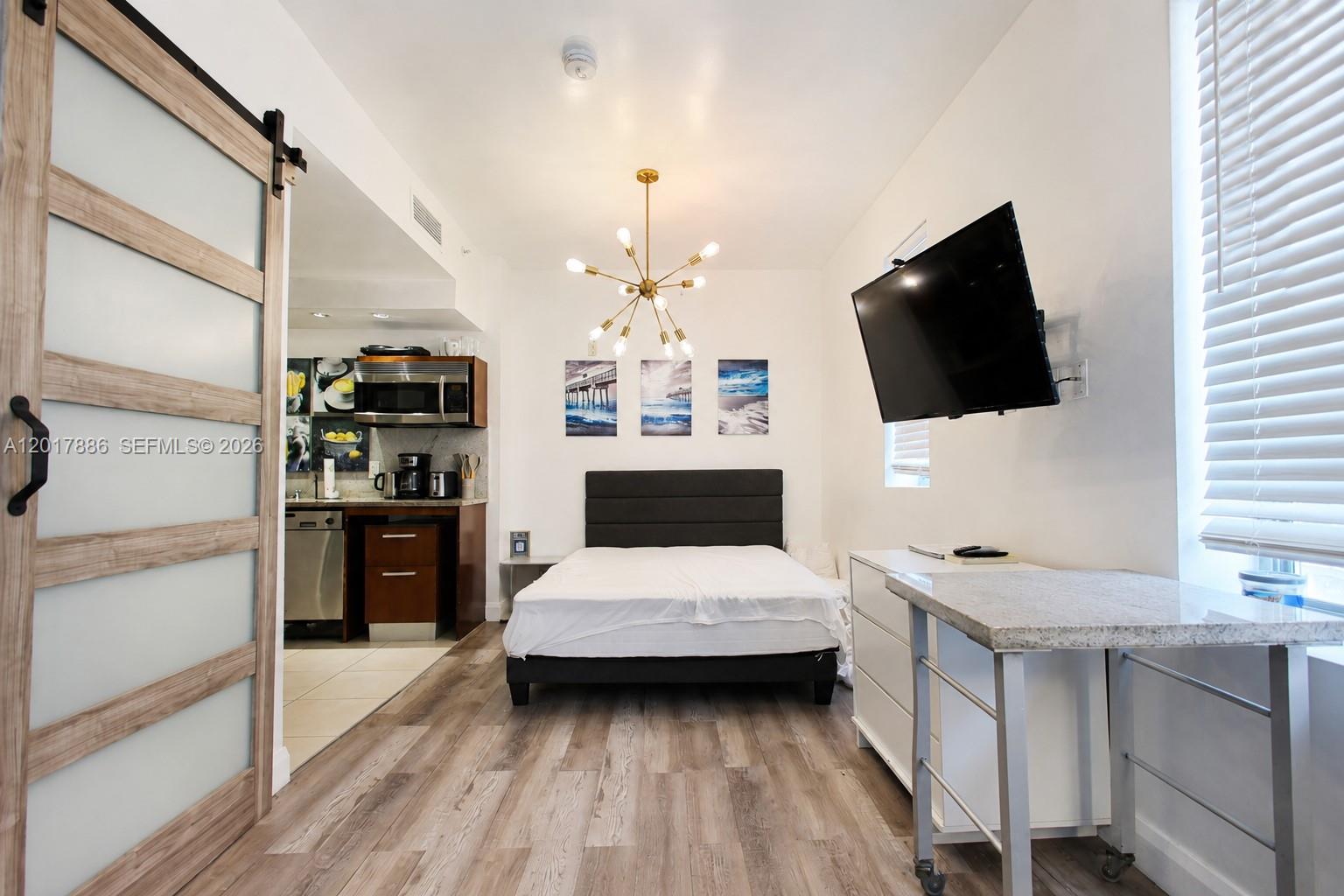 A studio apartment features a bed, a small kitchen, and a wall-mounted television — 1036 Ocean Dr # B308, Miami Beach FL 33139, MIAMI BEACH, FL