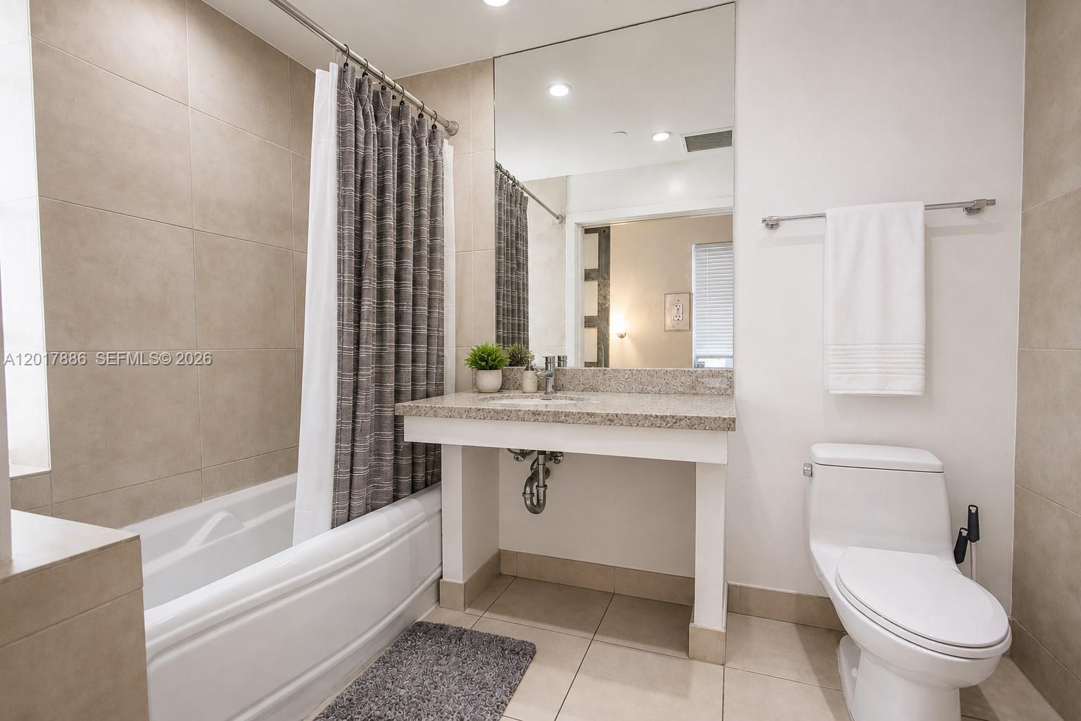 A bathroom features a bathtub with a shower curtain, a vanity, and a toilet — 1036 Ocean Dr # B308, Miami Beach FL 33139, MIAMI BEACH, FL