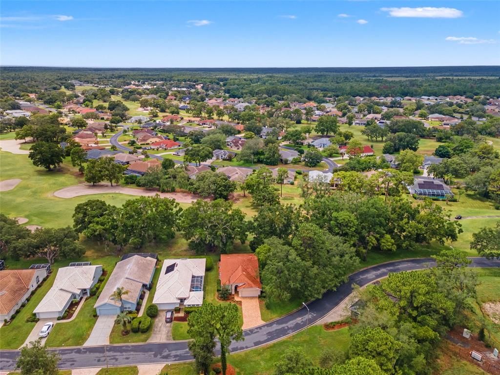 An aerial view shows a suburban neighborhood with houses, green lawns, and a golf course — 9419 NEW ORLEANS DRIVE, WEEKI WACHEE, FL