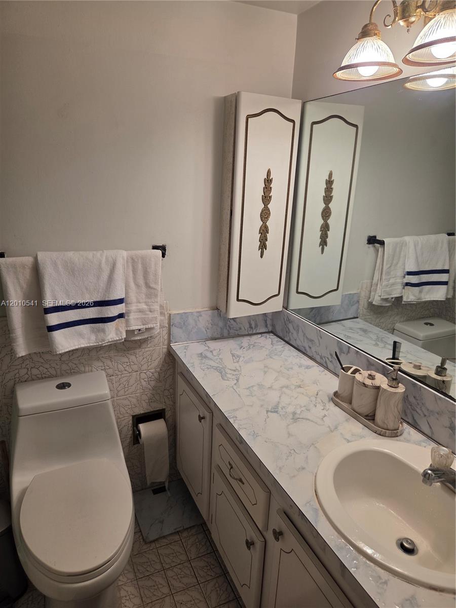 A bathroom features a white vanity with a blue-veined countertop, a toilet, and wall-mounted cabinets — 1817 S Ocean Dr # 325, Hallandale Beach FL 33009, HALLANDALE BEACH, FL