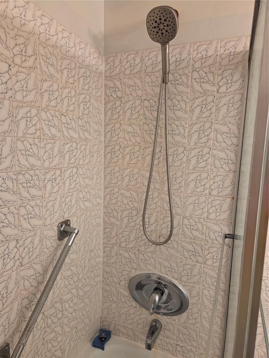 A shower stall features white patterned tile walls, a handheld showerhead, and a grab bar — 1817 S Ocean Dr # 325, Hallandale Beach FL 33009, HALLANDALE BEACH, FL