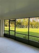 A screened-in porch with a concrete floor overlooks a grassy backyard and trees — 104 S COOPERS HAWK WAY, PALM COAST, FL
