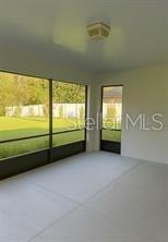 A screened-in porch with light-colored flooring, a ceiling light, and views of a grassy yard — 104 S COOPERS HAWK WAY, PALM COAST, FL