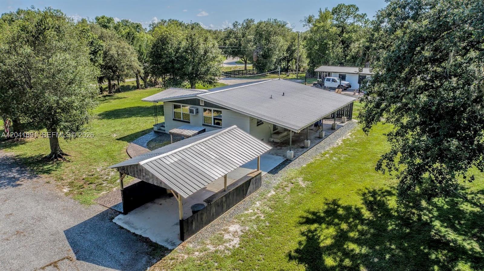 An aerial view shows a house with a metal roof and an attached carport — 1270 Nobles Rd, La Belle FL 33935, LA BELLE, FL
