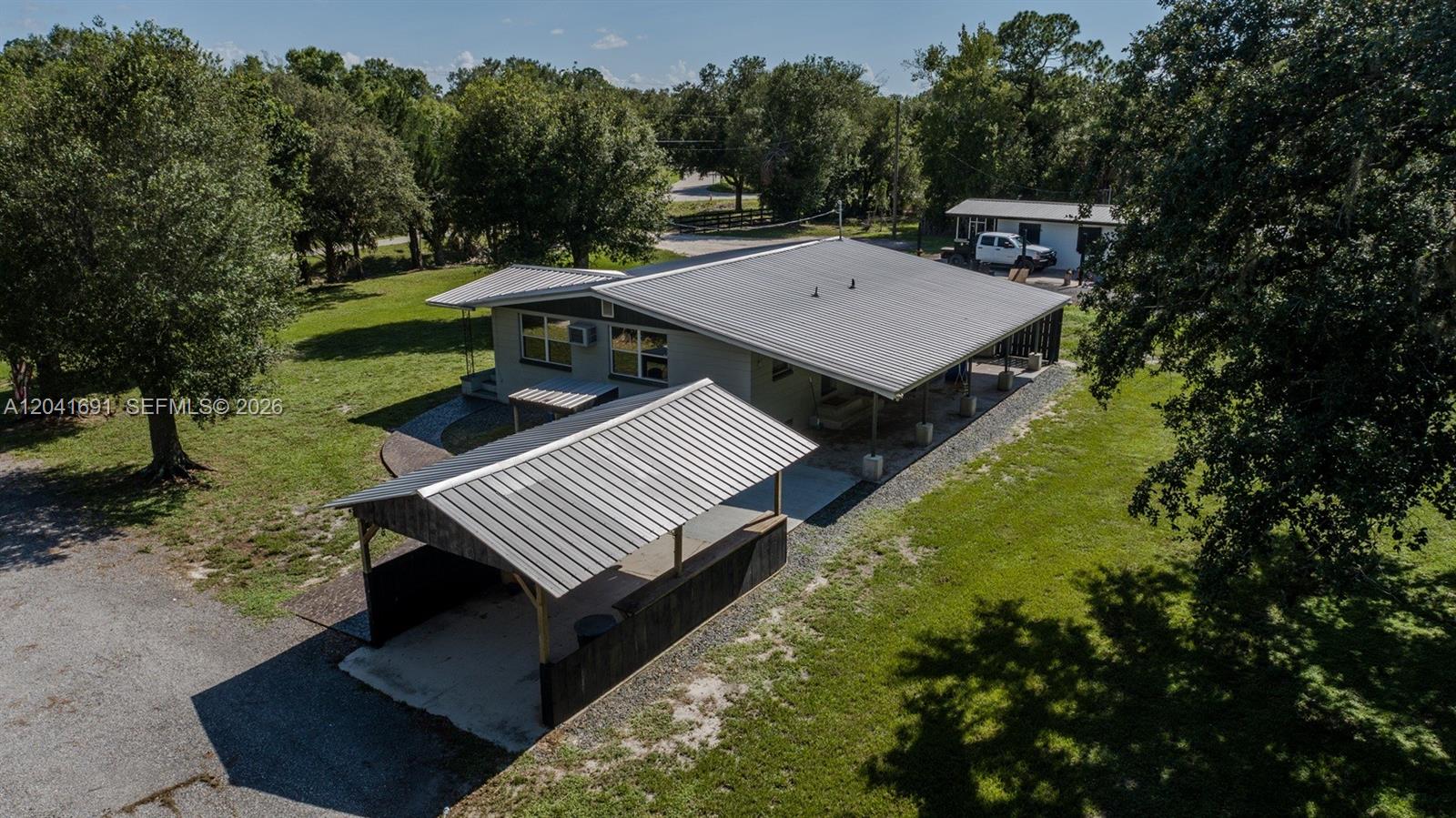 An aerial view shows a house with a metal roof and a detached carport — 1270 Nobles Rd, La Belle FL 33935, LA BELLE, FL