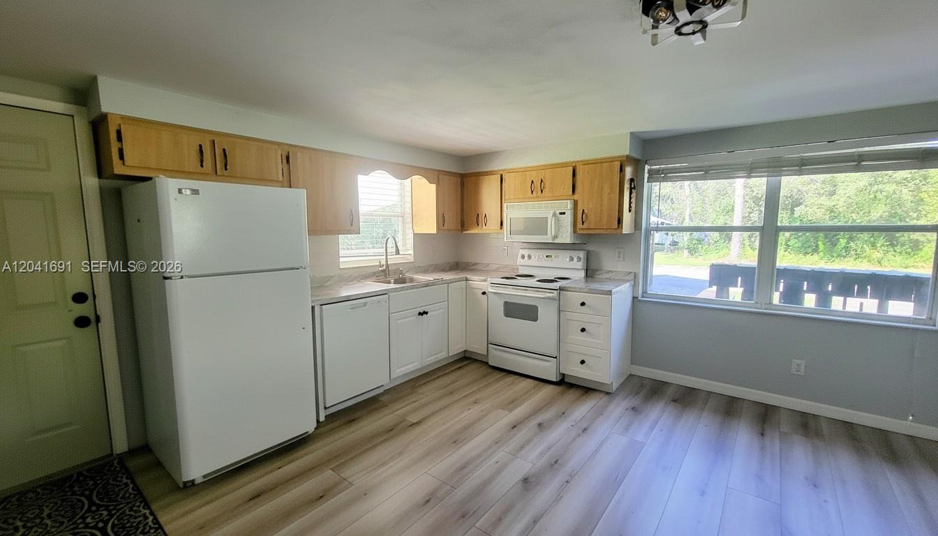 A kitchen features light wood cabinets, white appliances, and light-colored wood-look flooring — 1270 Nobles Rd, La Belle FL 33935, LA BELLE, FL