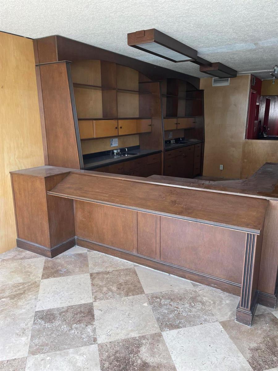 A wooden bar with built-in shelving and a sink sits on a checkered tile floor — FORT LAUDERDALE, FL