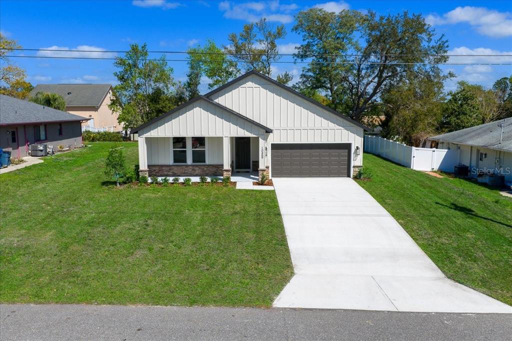 A single-story house with white vertical siding, a stone base, and a two-car garage — 10459 ABBEVILLE STREET, SPRING HILL, FL