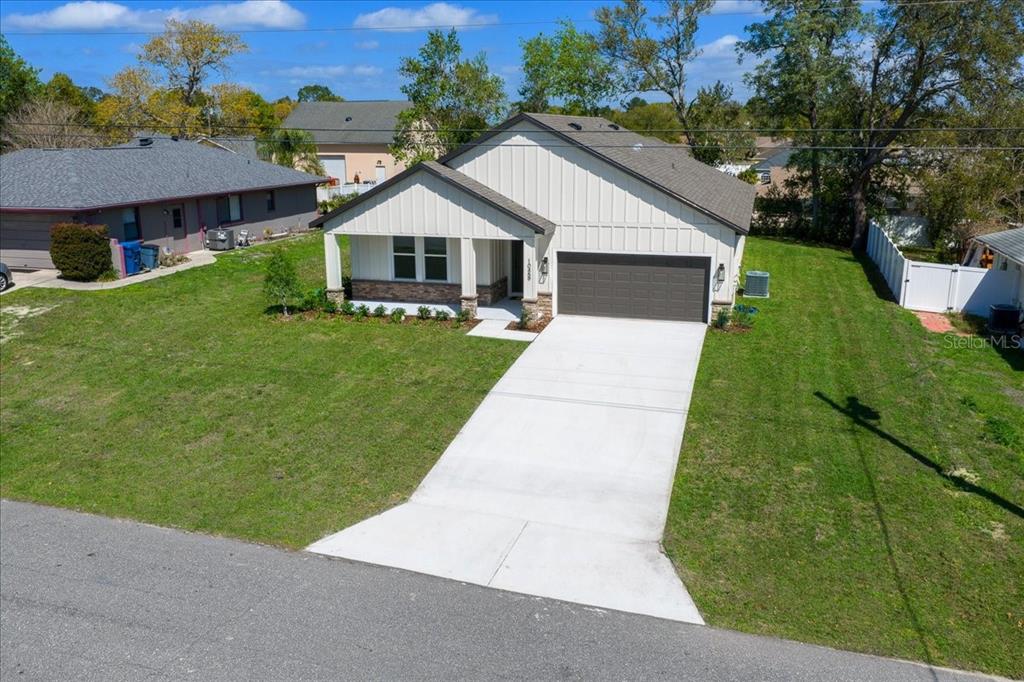 An aerial view of a single-story house with white vertical siding and a two-car garage — 10459 ABBEVILLE STREET, SPRING HILL, FL