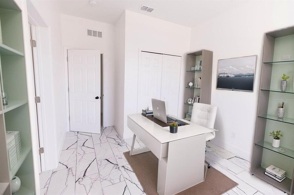 A home office features a white desk, marble-patterned tile flooring, and two tall shelving units — 67 W 10TH STREET, APOPKA, FL