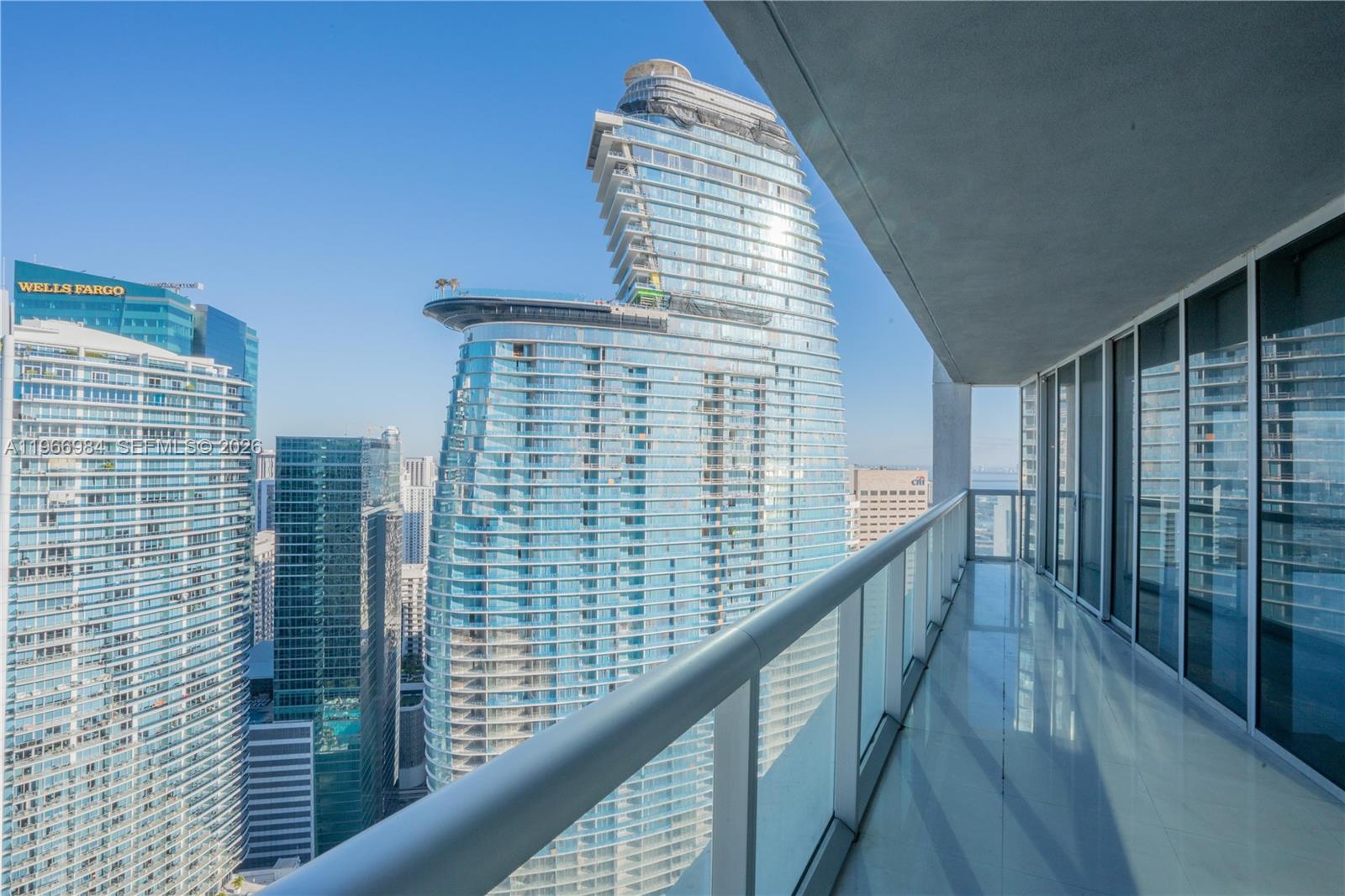 A balcony with a glass railing overlooks a dense urban skyline of modern glass skyscrapers — 465 Brickell Ave # 4802, Miami FL 33131, MIAMI, FL