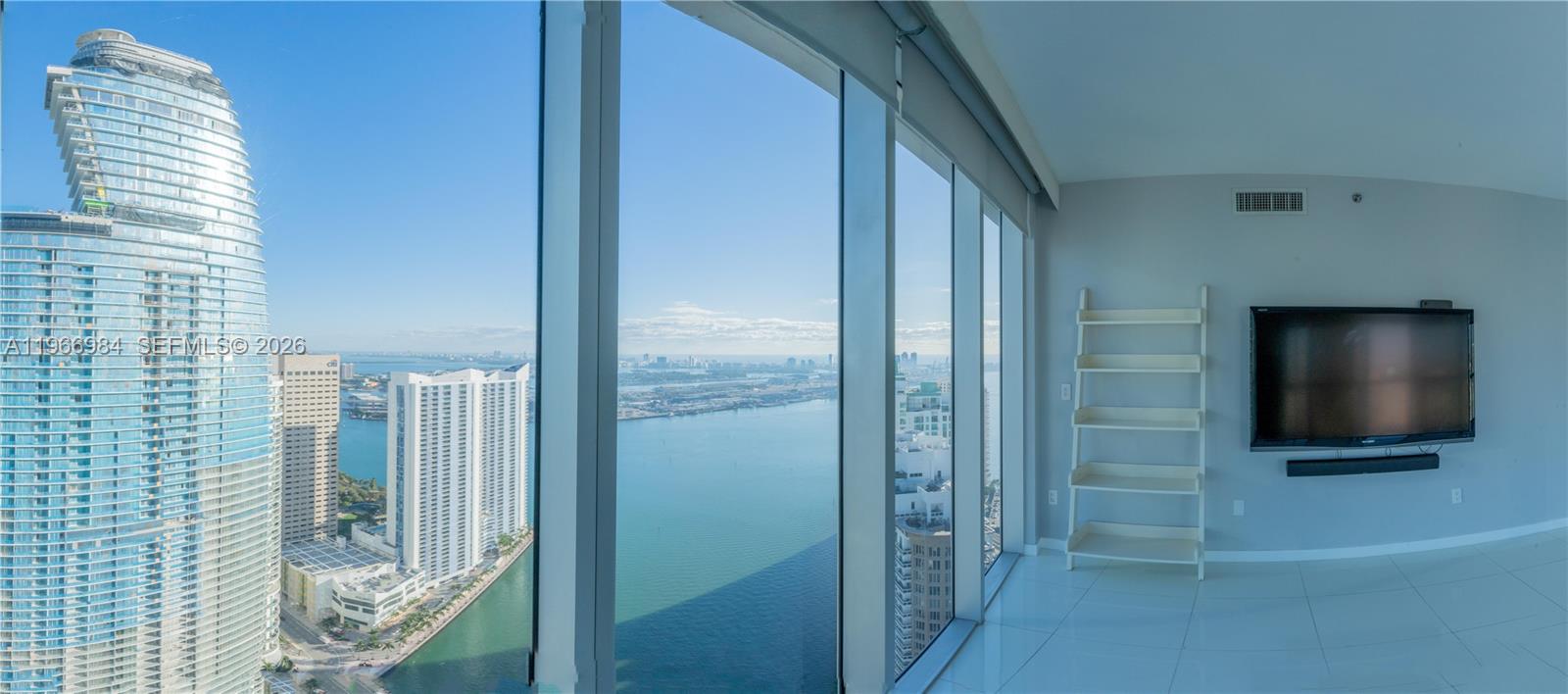 A high-rise room with white tile floors, a wall-mounted television, and floor-to-ceiling windows — 465 Brickell Ave # 4802, Miami FL 33131, MIAMI, FL