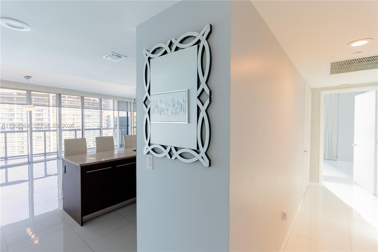 A modern interior features a decorative mirror on a wall beside a dining area — 465 Brickell Ave # 4802, Miami FL 33131, MIAMI, FL