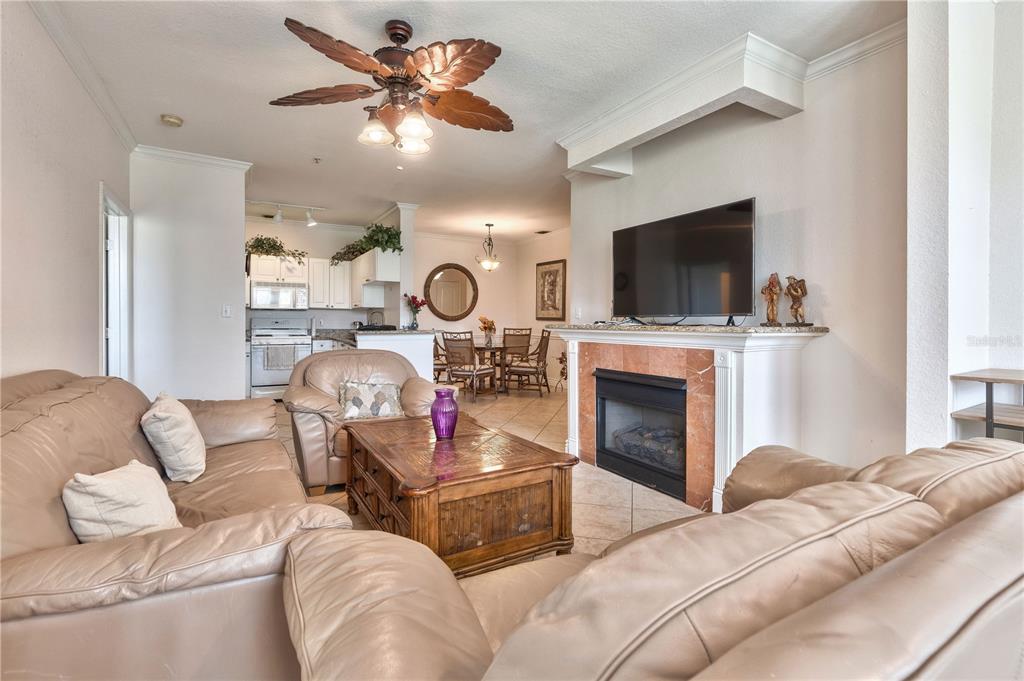 A living room with leather sofas, a coffee table, and a fireplace beneath a television — 2732 VIA MURANO UNIT 526, CLEARWATER, FL