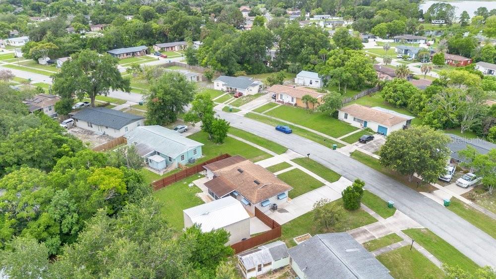 An aerial view shows a suburban neighborhood with several single-story houses, driveways, and mature trees — 1109 COBBLESTONE AVENUE, DELTONA, FL
