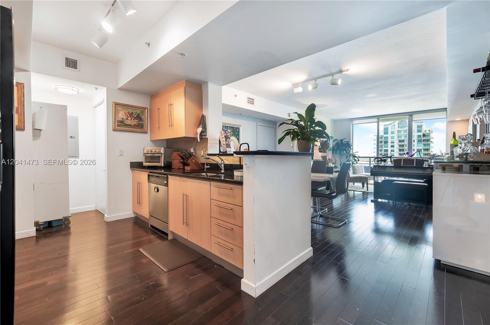 A kitchen with light wood cabinets and dark countertops opens into a living area — 325 S Biscayne Blvd # 3921, Miami FL 33131, MIAMI, FL
