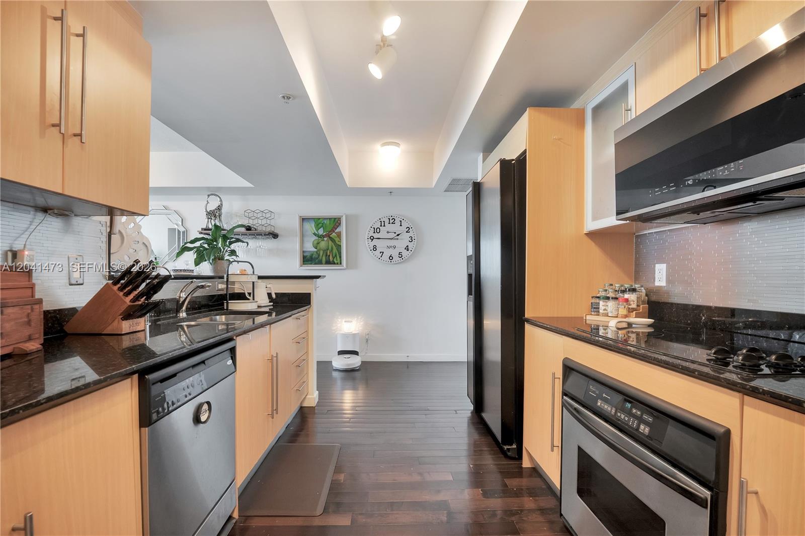 A galley kitchen features light wood cabinets, black granite countertops, and stainless steel appliances — 325 S Biscayne Blvd # 3921, Miami FL 33131, MIAMI, FL