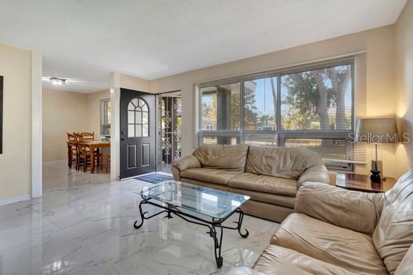 A living room with light tile flooring, a tan sofa, and a glass coffee table — 635 MCCORMICK STREET, DAYTONA BEACH, FL