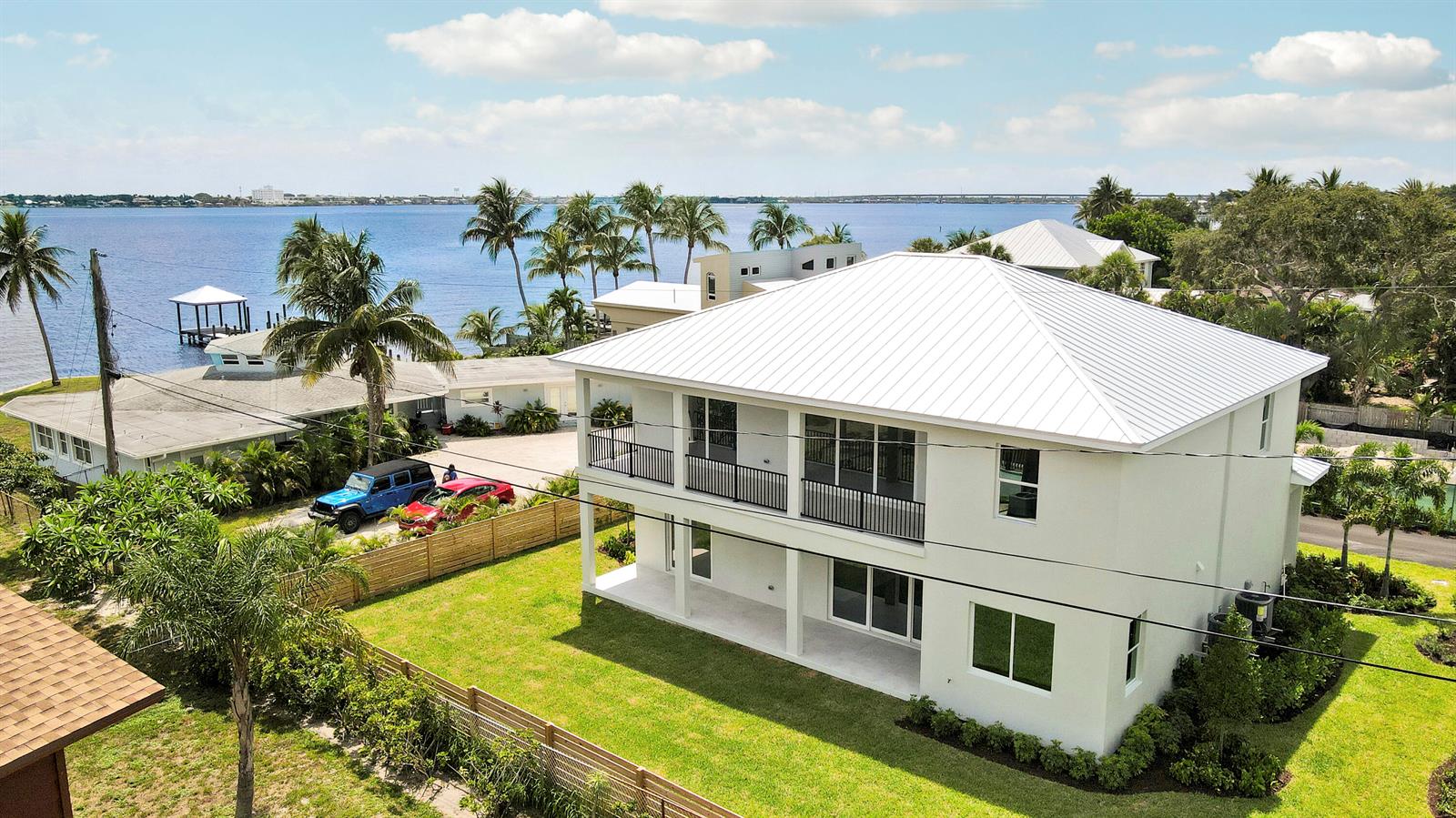 An aerial view of a two-story white house with a metal roof near the water — 1013 NE Orange Avenue, Jensen Beach FL 34957, JENSEN BEACH, FL