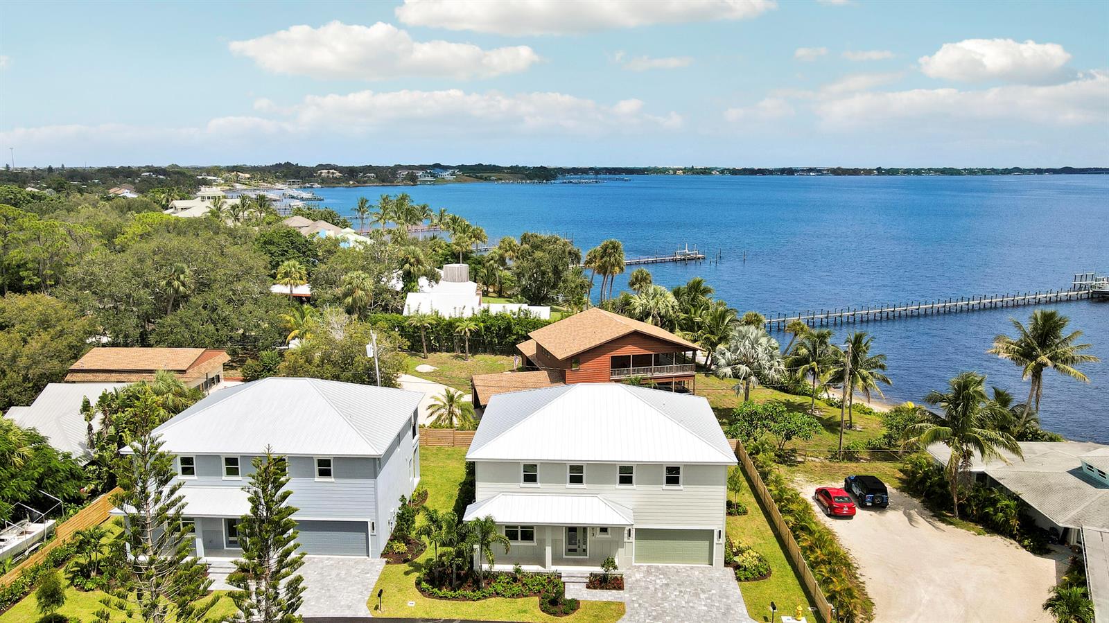 An aerial view shows two modern houses near a large body of water with docks — 1013 NE Orange Avenue, Jensen Beach FL 34957, JENSEN BEACH, FL