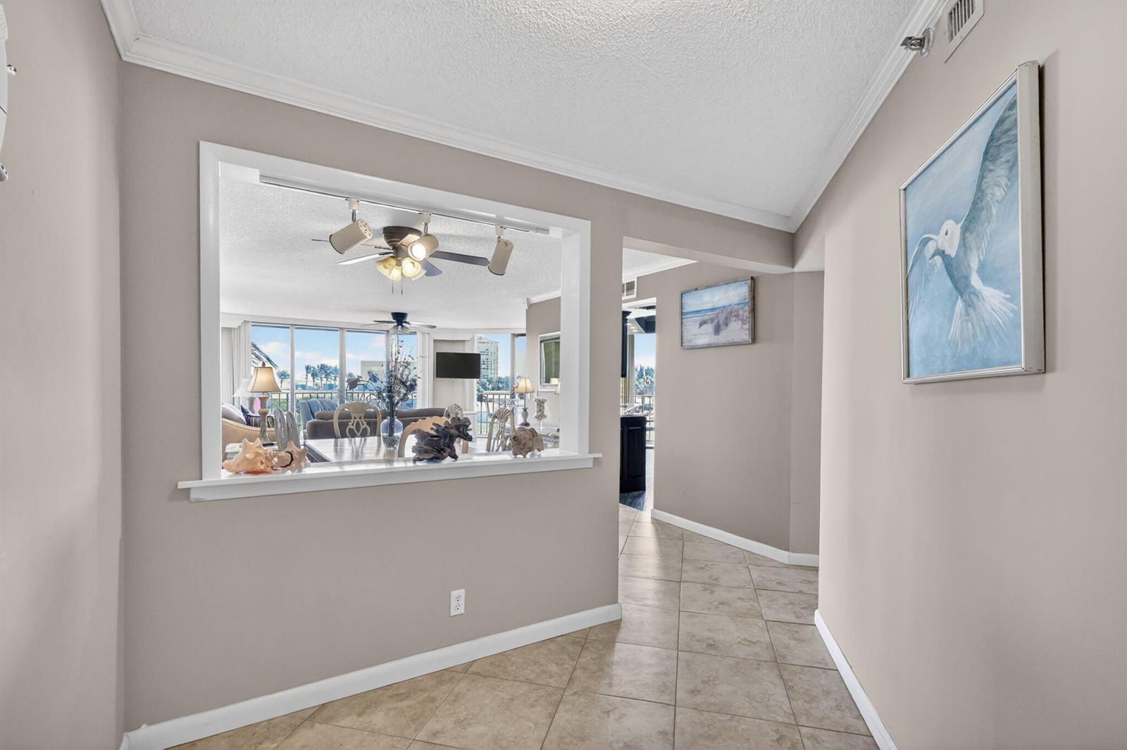 A hallway with tile floors leads to an open pass-through window into a living area — 9650 S Ocean Drive # 210, Jensen Beach FL 34957, JENSEN BEACH, FL