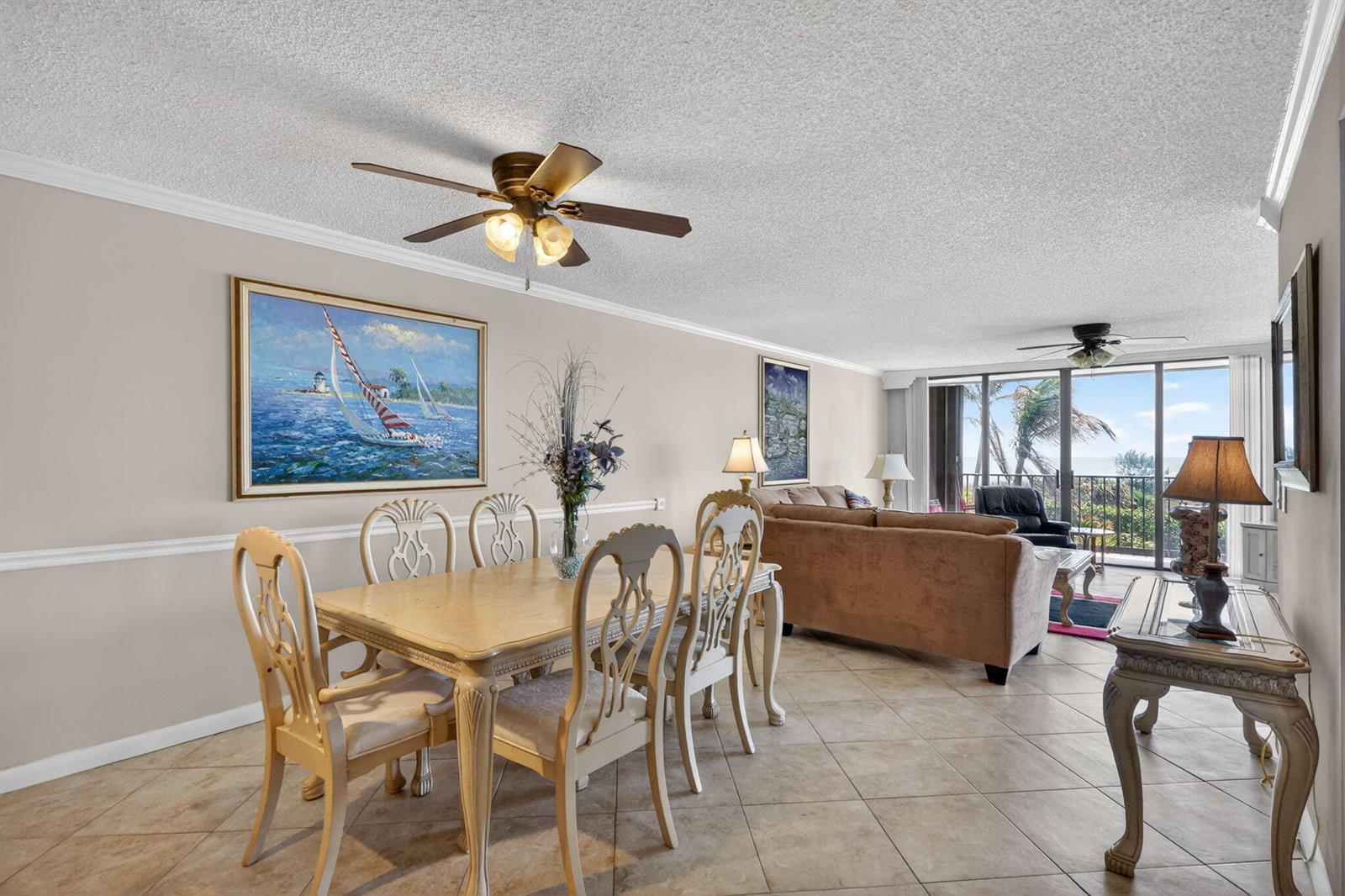 A dining area with a wooden table and chairs opens into a living room with balcony — 9650 S Ocean Drive # 210, Jensen Beach FL 34957, JENSEN BEACH, FL