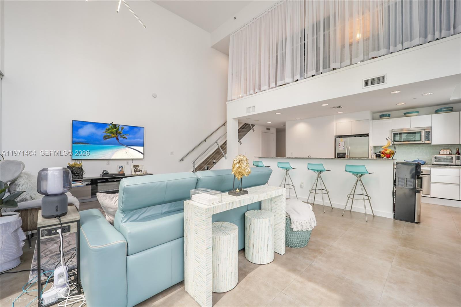 A modern open-concept living room and kitchen with high ceilings and a lofted area — 1060 Brickell Ave # 1003, Miami FL 33131, MIAMI, FL