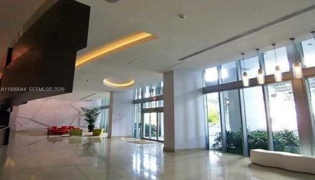 A modern building lobby features high ceilings, floor-to-ceiling windows, pendant lighting, and polished floors — 79 SW 12th St, Miami FL 33130, MIAMI, FL