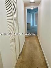 A narrow hallway with beige carpet leads toward a bright room with white walls — 79 SW 12th St, Miami FL 33130, MIAMI, FL