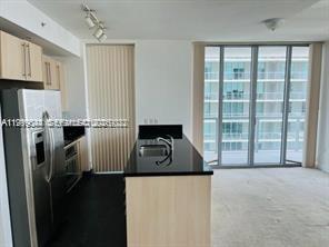 A kitchen with light wood cabinets, black countertops, and a stainless steel refrigerator — 79 SW 12th St, Miami FL 33130, MIAMI, FL