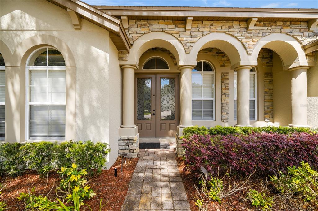 A stone-paved walkway leads to the arched entryway of a stucco home with double doors — 2928 PARK MEADOW DRIVE, APOPKA, FL