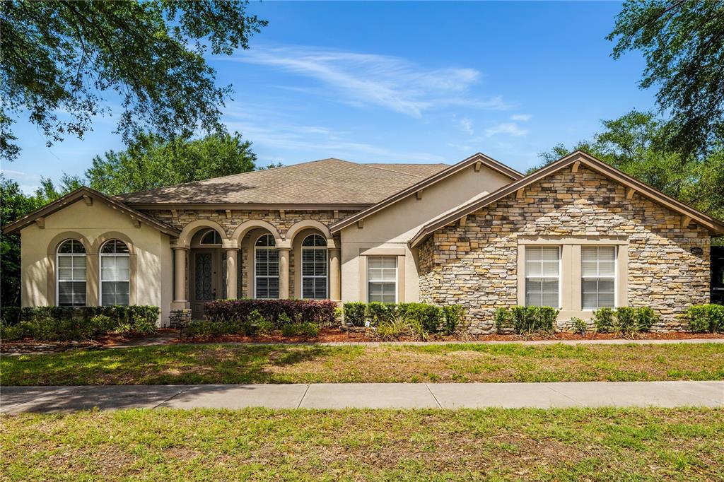 A single-story house features a stone facade, arched windows, and a covered entryway — 2928 PARK MEADOW DRIVE, APOPKA, FL