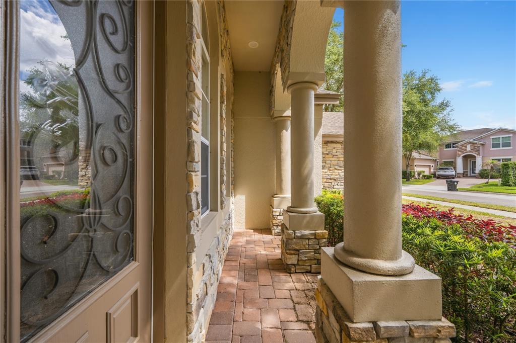 A covered front porch features stone-clad columns, a brick paver floor, and a decorative door — 2928 PARK MEADOW DRIVE, APOPKA, FL