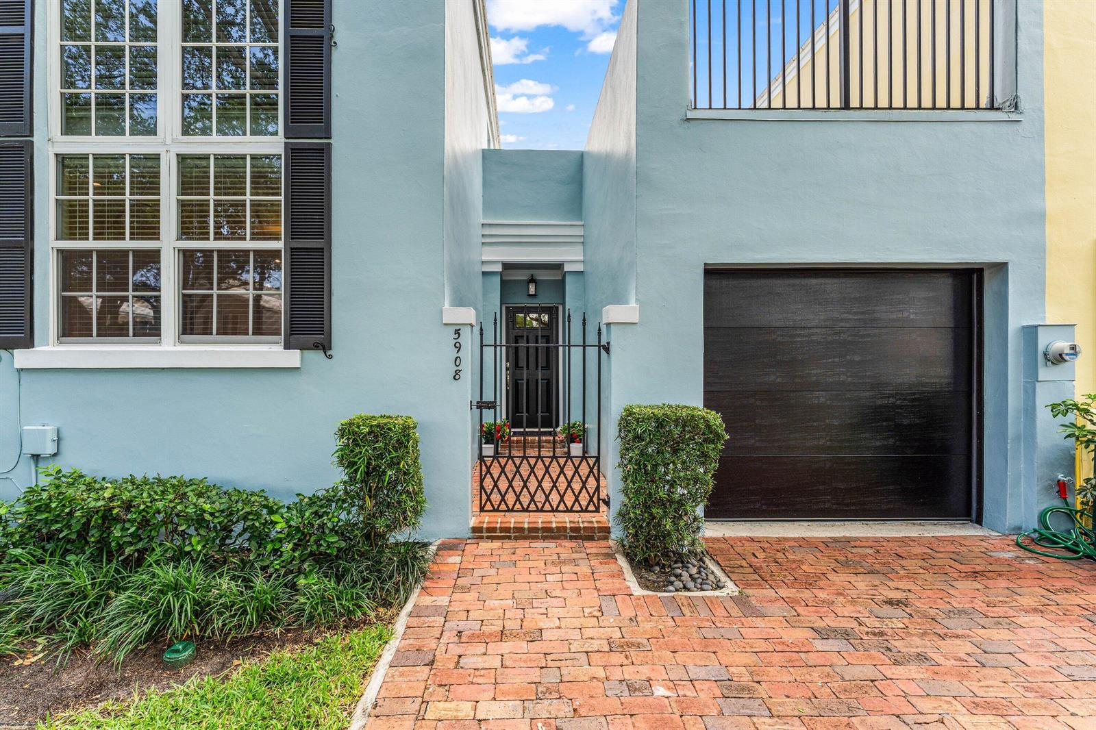The exterior of a light blue house features a brick walkway, a gated entryway, and garage — 5908 Catesby Street, Boca Raton FL 33433, BOCA RATON, FL