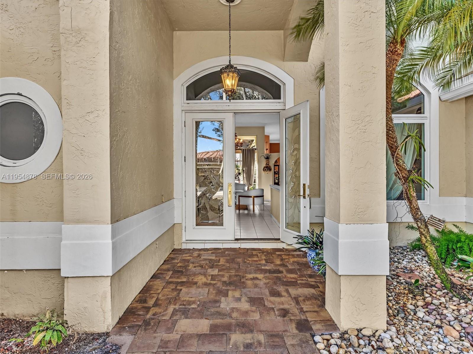 A paved entryway leads to a double glass door under a hanging lantern light — 900 Spoonbill Cir, Weston FL 33326, WESTON, FL