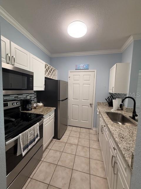 A galley kitchen features white cabinets, stainless steel appliances, granite countertops, and light blue walls — 1216 S MISSOURI AVENUE UNIT 227, CLEARWATER, FL